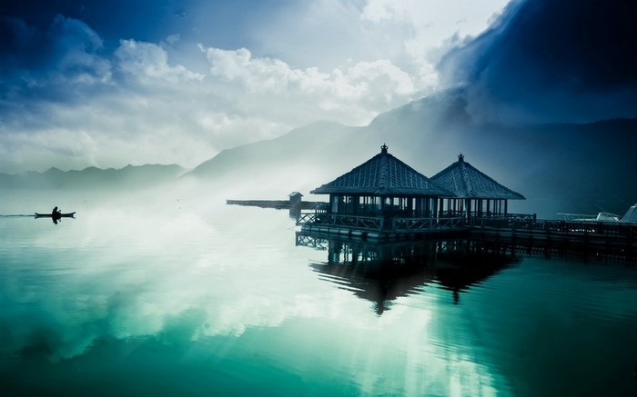 Kayaker on a misty lake with floating pavilions