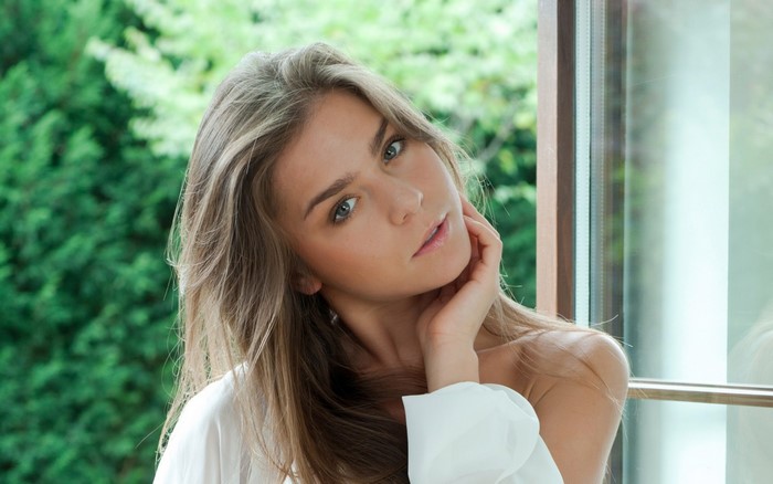 Woman with long brown hair by the window