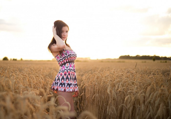 Woman in patterned dress in a wheat field at sunset