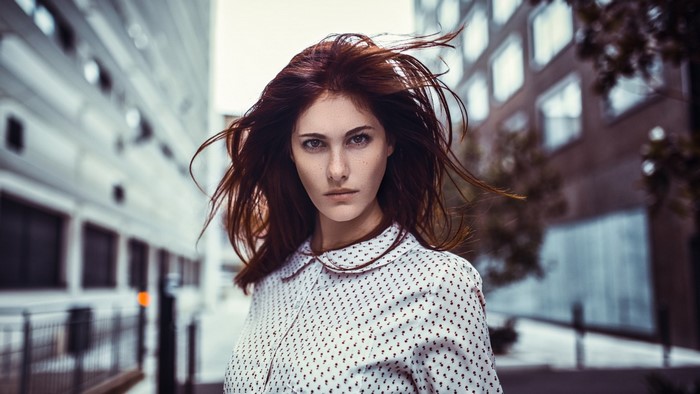 Woman with red hair looking at viewer in urban setting
