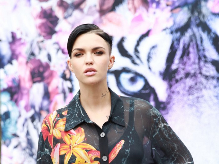 Ruby Rose posing in front of a floral and tiger print background