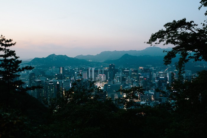 Cityscape at dusk with mountains and trees