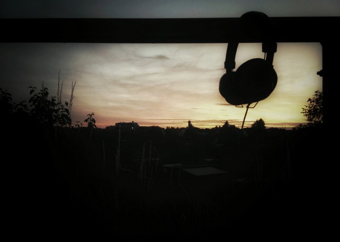 Headphones hanging against a sunset sky over a landscape
