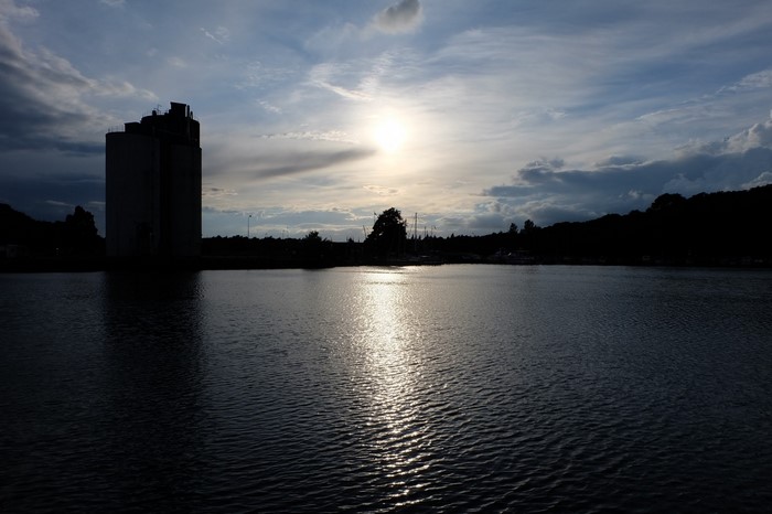 Silhouetted grain elevator by the water at sunset