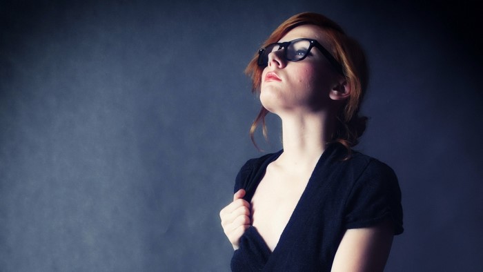 Woman with red hair and glasses looking up