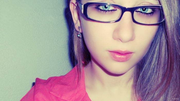 Woman with blue eyes and glasses wearing pink shirt