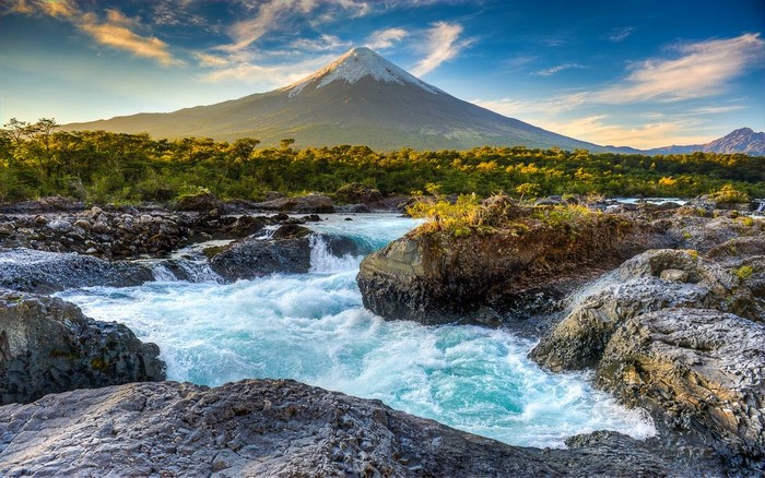 Volcano with snowy peak overlooking a river and forest