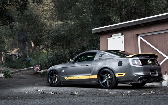 Gray Ford Mustang with yellow accents parked near a building