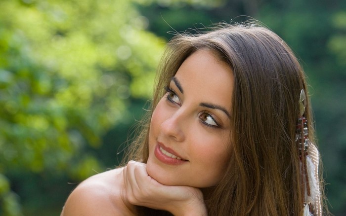 Woman with brown hair and feather accessory