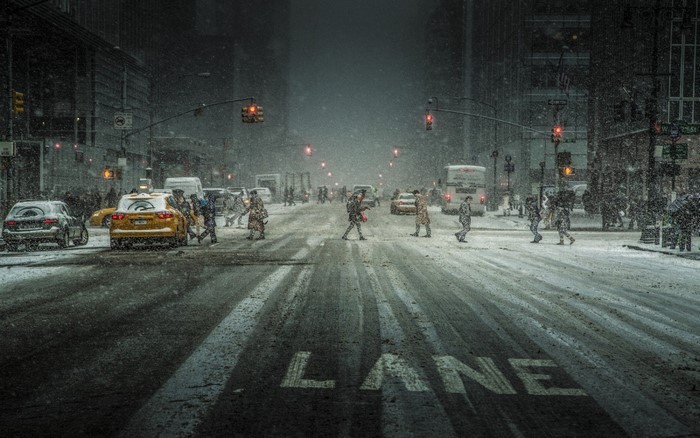 People crossing a snowy street in a city