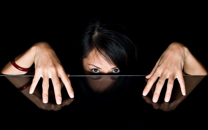Woman peeking over a reflective surface with hands on it