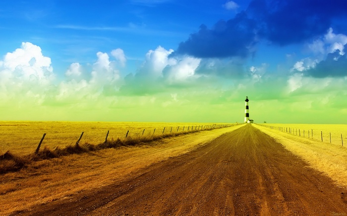 Dirt road leading to a lighthouse in a field
