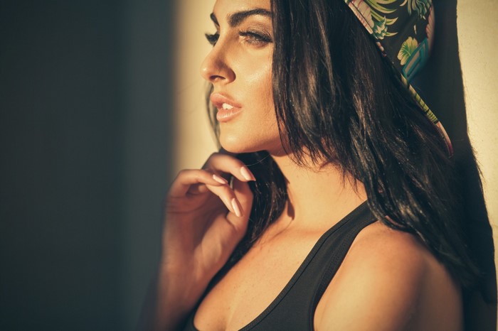 Woman with brown hair wearing a black tank top and bandana