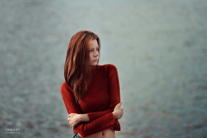 Redhead woman in red sweater by the water