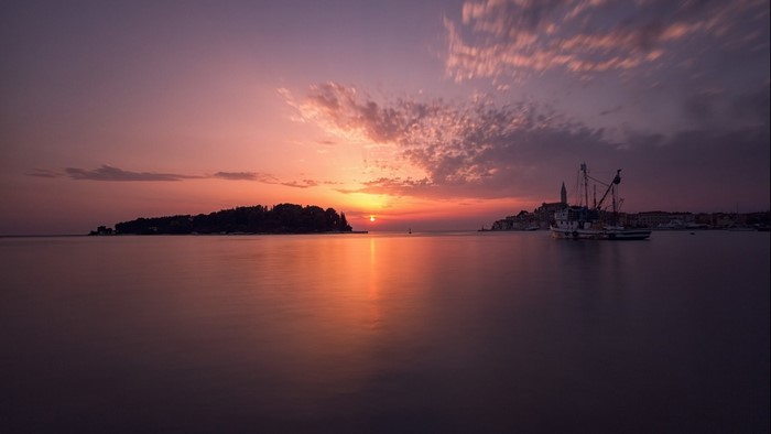 Sunset over the sea with islands and a boat