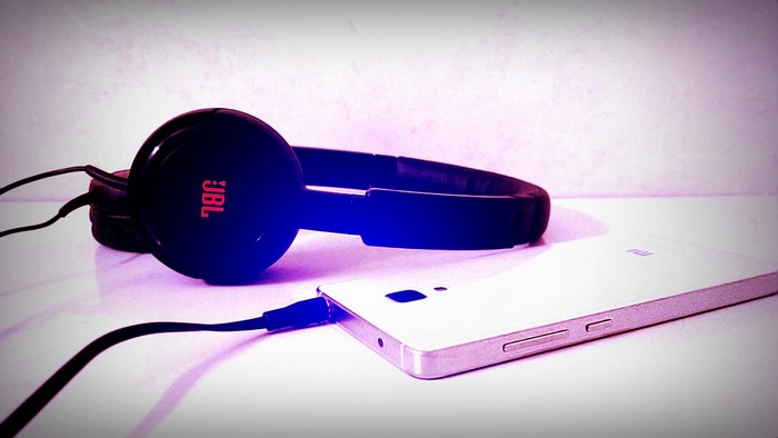 Black JBL headphones connected to a white Xiaomi smartphone