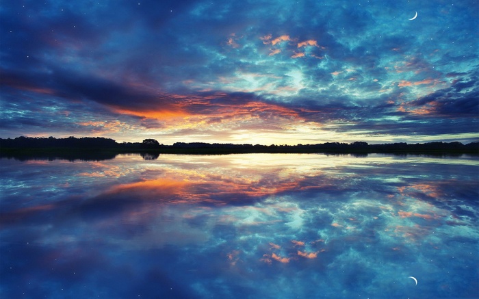 Sunset over a calm lake with colorful clouds and moon