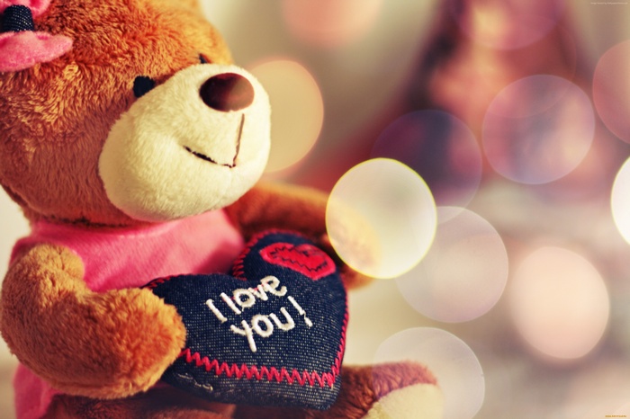 Teddy bear holding a heart that says "I love you!"