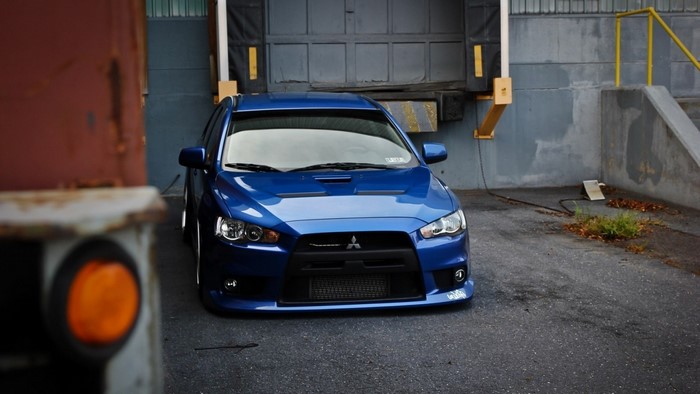 Blue Mitsubishi Lancer Evolution parked near a loading dock