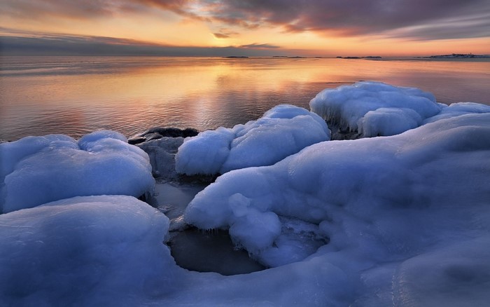 Frozen coast at sunset with calm sea reflection