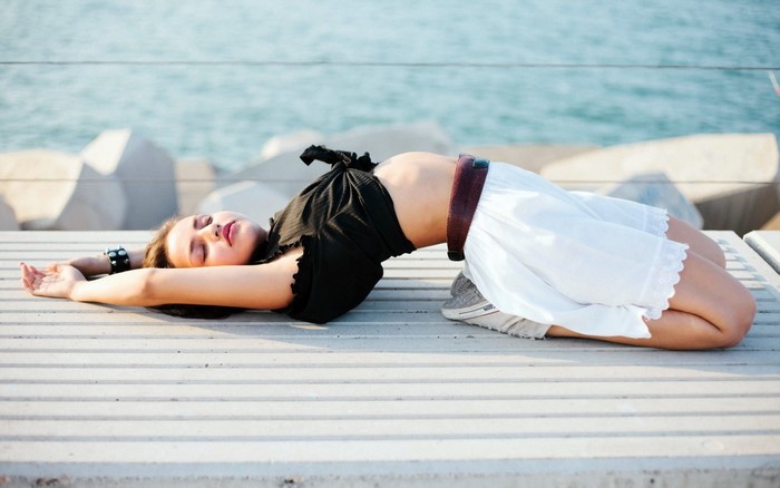 Woman arching back on a deck by the water