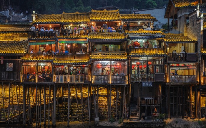 Buildings on stilts with people dining at night
