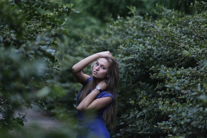 Woman in blue dress posing in a green forest