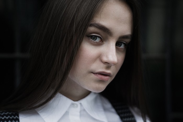 Woman with long brown hair wearing a white shirt