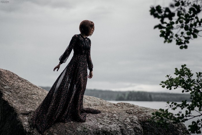 Woman in a floral dress on a rock by the water