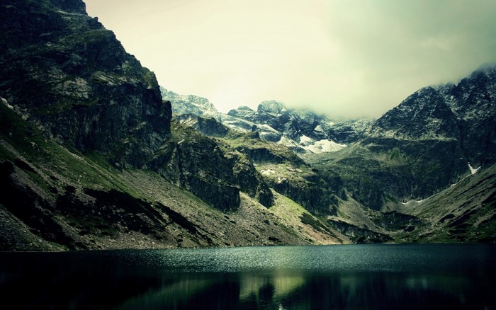 Mountain lake with rocky slopes and overcast sky