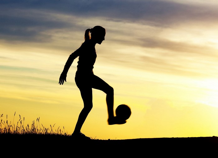 Silhouette of a woman playing soccer at sunset