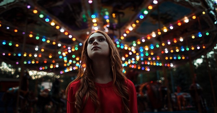 Woman looking up at colorful carousel lights at night