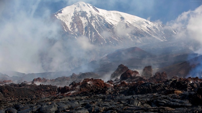 Volcano with snow-capped peak and lava field in Kamchatka, Russia
