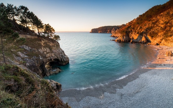 Rocky coast with turquoise bay at sunset