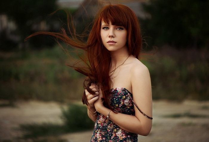 Young woman with long red hair in a floral dress