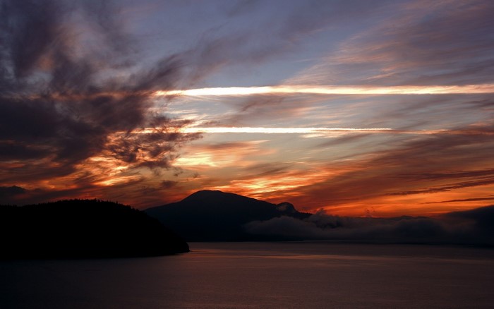 Sunset over a lake with mountains and clouds