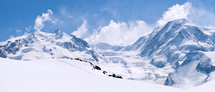 Snowy mountains under a blue sky with clouds