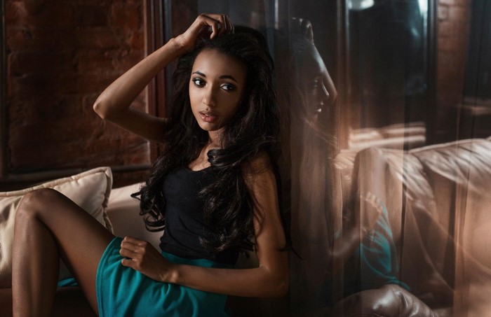 Woman with long dark hair posing on a couch