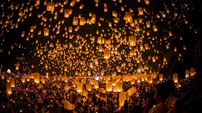 Thousands of lanterns released by a crowd at night
