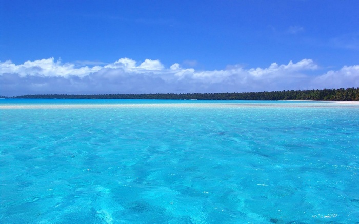 Turquoise ocean water with a distant island and blue sky