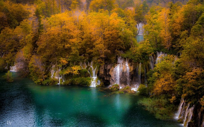 Autumn forest with waterfalls and a turquoise lake