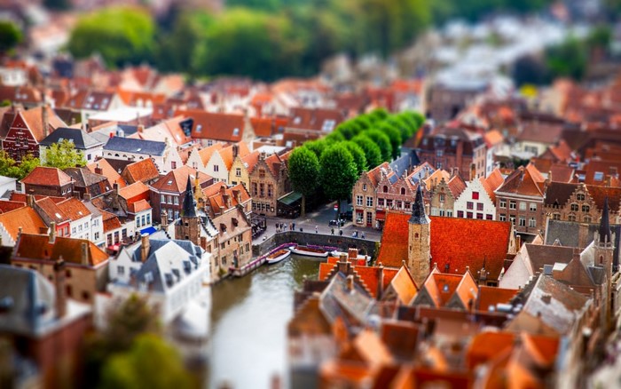 Tilt shift cityscape of Bruges with canal and trees