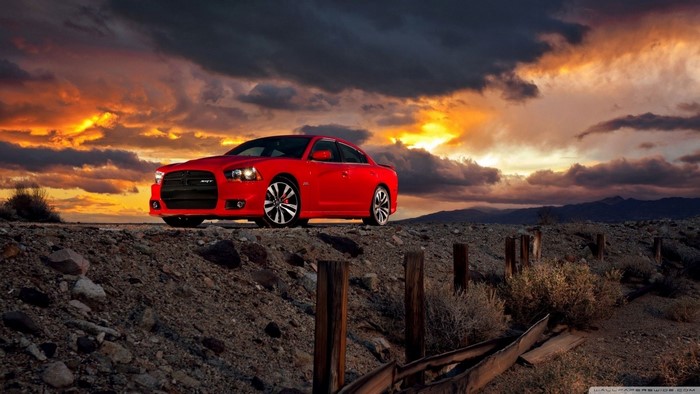 Red Dodge Charger SRT on a rocky road at sunset