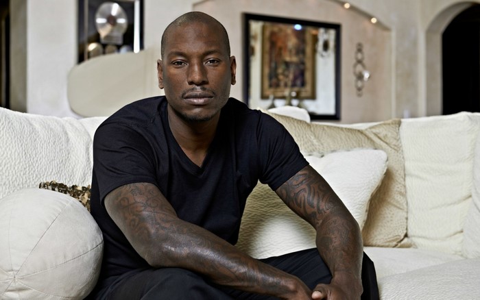 Tyrese Gibson sitting on a couch with tattoos