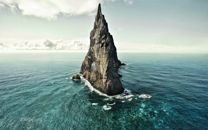 Tall rock formation in the ocean with waves