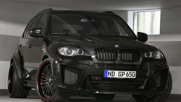 Black BMW X6 with custom rims parked indoors