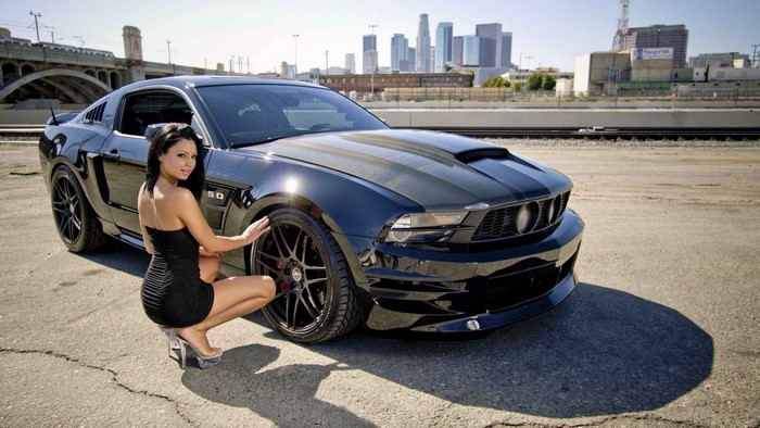 Woman posing with a black Ford Mustang Shelby GT500