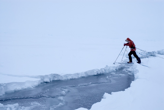 Man cross-country skiing over icy water