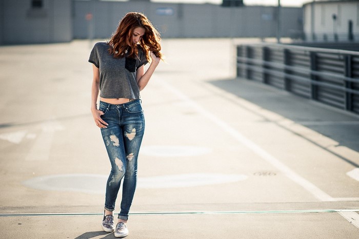Woman with red hair wearing ripped jeans and a crop top