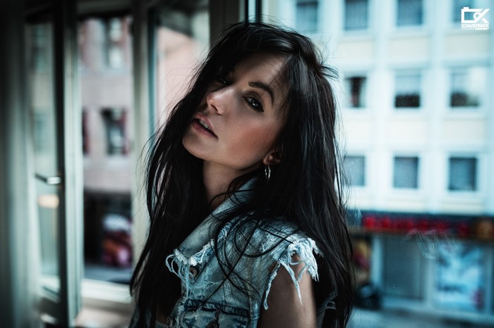 Woman with dark hair wearing denim vest